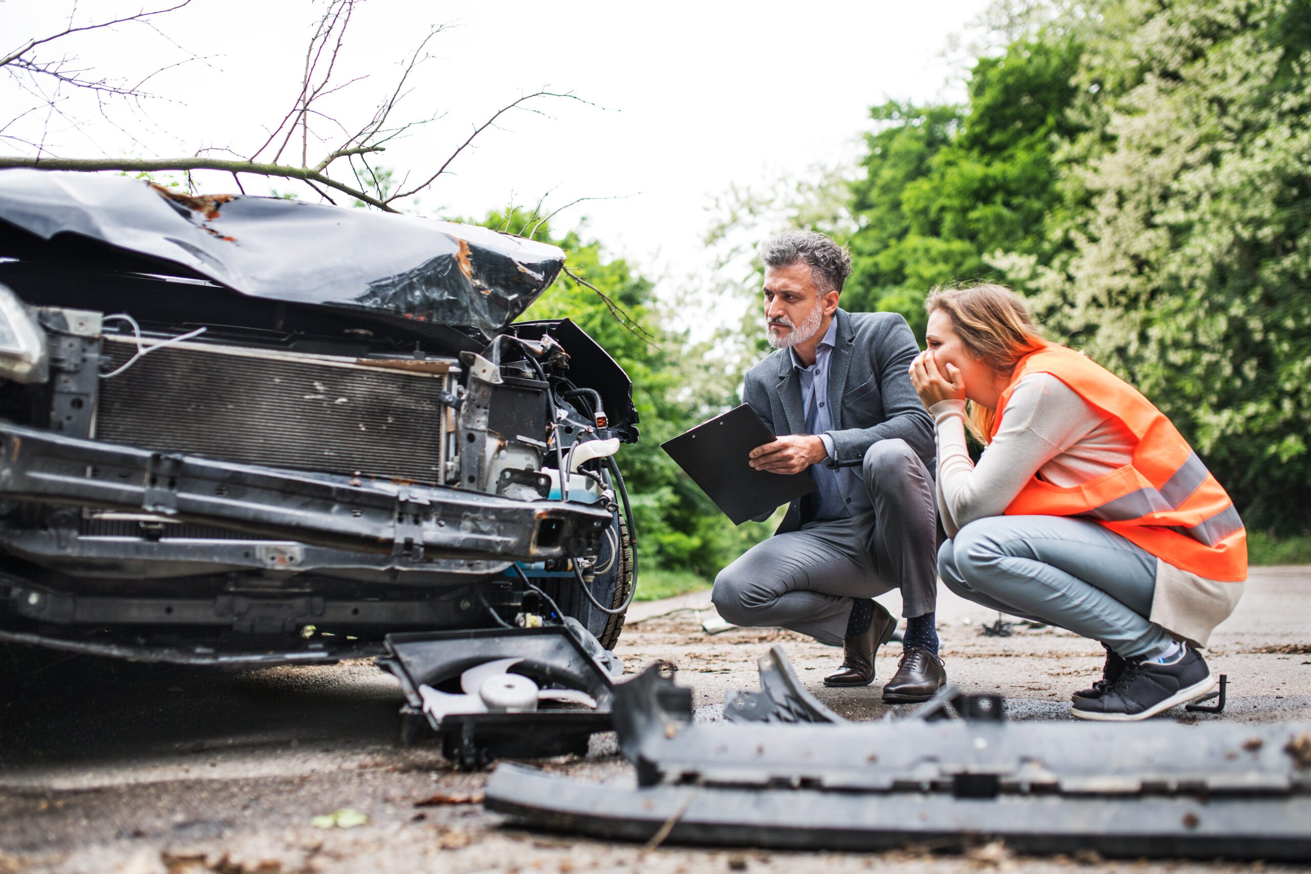 Two people looking at a wrecked car
